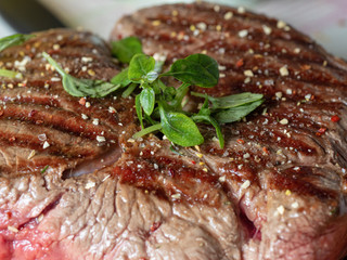 A large piece of juicy fresh beef sprinkled with spices and herbs. Stripes-rare, the juice from the meat. Close-up, front view