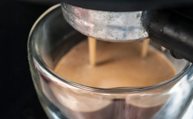 The coffee maker. Close shot. Coffee in a double-walled glass cup. Coffee is poured from a coffee machine in the morning