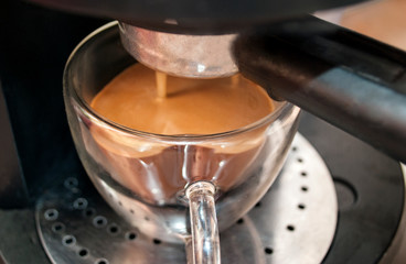 The coffee maker. Close shot. Coffee in a double-walled glass cup. Coffee is poured from a coffee machine in the morning