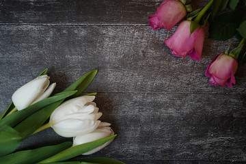 Tulips and roses on a wooden table. space for text. postcard for spring holidays