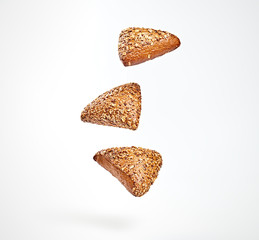 Multigrain bun flying in air. Fresh baked cookie with sunflower, flax, sesame falling on white. Delicious healthy bread bakery product with different seed. Levitation, fly dieting baking concept