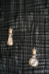 Fototapeta na wymiar Decorative style antique edison light bulbs on the dark gray wall background. Loft interior details, decor in restaurant on wedding.