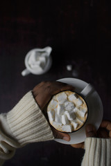  Female hands holding a cup of coffee with marshmallows in the cup