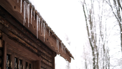 Winter, the roof of the house covered with white snow and hanging icicles