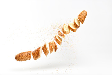 Baguette with sesame seed flying in air. Fresh baked bread sliced, cut. Traditional bakery product french baguette. Delicious crispy wheat bread, levitation, fly food concept
