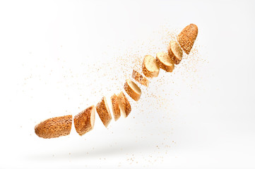 Baguette with sesame seed flying in air. Fresh baked bread sliced, cut. Traditional bakery product...