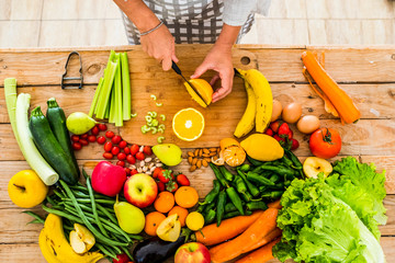 Top view of woman chef cutting and preparing healthy natural food on a wooden table - vegatbles and...