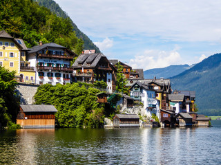Fototapeta na wymiar Small village located by the lake in Hallstatt, Austria. The houses have many different colors. Alpine village. Idyllic landscape. Coexistence of human and nature. High mountains rising from the lake