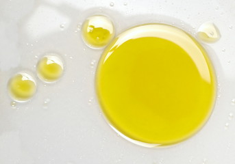Puddle of natural olive oil in water background, top view