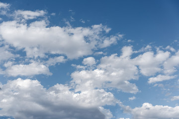 White cumulus clouds against the background against blue on a blue background.