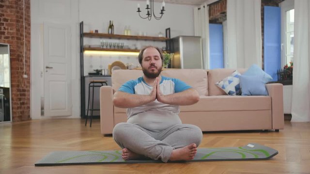 Obese man losing weight doing exercises at home
