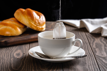 Fresh and rosy buns with cherry on a wooden table and a cup with fragrant tea.