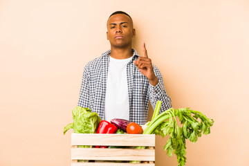 Young farmer man isolated on a beige background showing number one with finger.