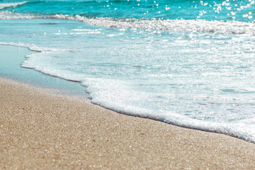 Background of sandy beach and foamed sea water in summer.
