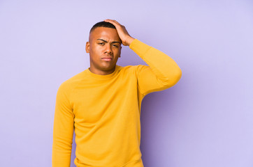 Young latin man isolated on purple background tired and very sleepy keeping hand on head.