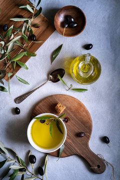 Overhead view of Fresh black olives and extra virgin olive oil  with olive branches arranged on wooden chopping boards