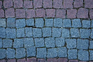 Paving stones made of natural stone. Paths for pedestrians. Beautiful multi-colored square-shaped stones. The view from the top. Background