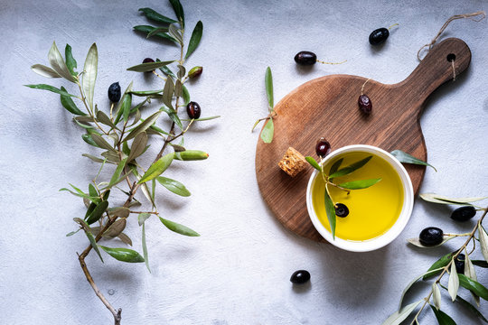 Overhead view of Fresh black olives and extra virgin olive oil with olive branches arranged on a wooden chopping boards