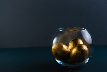 gilded easter eggs in a transparent vase on a concrete background in classic blue color