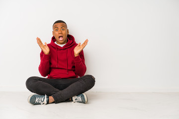 Young latin man sitting on the floor isolated surprised and shocked.