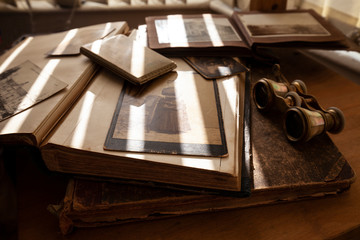 Old photos, books, album, binoculars, cigarette case in shallow deep of field.