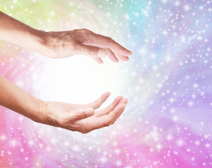 Creating a Healing Rainbow Energy Vortex from White Light - female cupped hands with a spiralling rainbow coloured sparkling background and a ball of white light plus copy space 