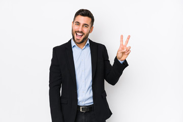 Young caucasian business man against a white background isolated joyful and carefree showing a peace symbol with fingers.