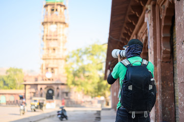 Rear view of photographer capturing Jodhpur clork tower Ghanta Ghar in city square