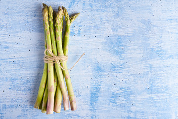 Bunch of fresh asparagus on blue background. Exotic vegetable for healthy nutrition and diet. Top view. Copy space, minimalism concept for design - Powered by Adobe