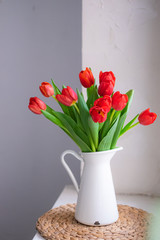 Beautiful tulip bouquet in white vase on white rustic background. lifestyle close up