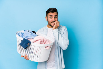 Young handsome man doing laundry isolated biting fingernails, nervous and very anxious.