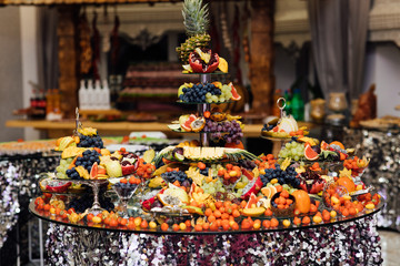 Catering table with different kind of fruits. Wedding reception catering table with different fruits. Carved fruits arrangement. Fresh various fruits. Assortment of exotic fruits. 