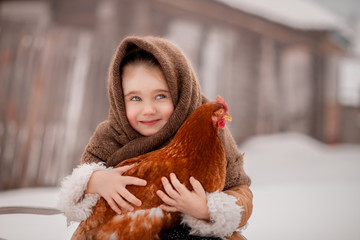 Cute little girl holding a red chicken