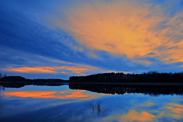 Landscape of a spring sunset at Crooked Lake, with reflections in calm water, Michigan, USA