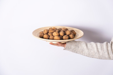 Shelled walnuts women's hand in wooden plate. Healthy and natural food, snacks.