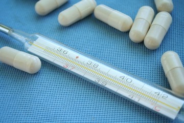 Tablets, pills and mercury thermometer on a blue background. Flu cold concept. Healthcare medical...