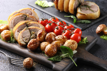Concept of Russian cuisine. Meatloaf with pesto sauce and baked potatoes, fresh tomatoes and spinach on a dark background. Background image, copy space