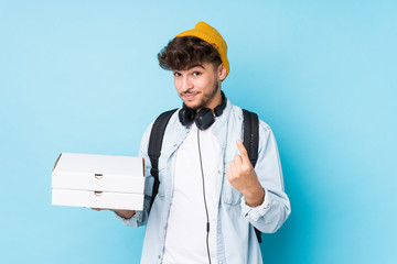 Young arab student man holding pizzas isolated pointing with finger at you as if inviting come closer.