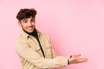 Young arabian man posing in a background isolated holding a copy space on a palm.