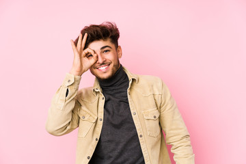 Young arabian man posing in a background isolated excited keeping ok gesture on eye.