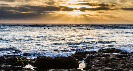 Surfers on wave during Sunset