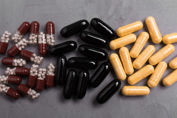 Three piles of capsule pills on gray background