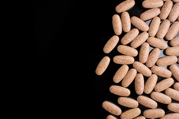Large pills on a black background on the right side of the frame, place for text.