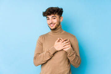 Young arabian man isolated has friendly expression, pressing palm to chest. Love concept.