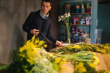 Male make spring bouquet. Gardener's in the flower shop make bouquet. Lifestyle flower shop. Beautiful flower composition of yellow flowers