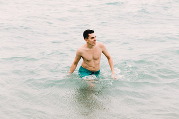 a young guy is swimming in the blue clear water of the ocean