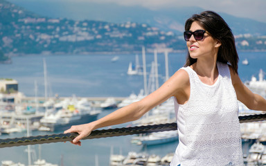 Fototapeta na wymiar Young Woman Traveler Enjoying the View on the Harbor with Yachts in Monte Carlo, Monaco in the Summer