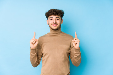 Young arabian man isolated indicates with both fore fingers up showing a blank space.