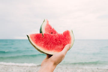 a slice of ripe juicy watermelon in the hands of the sea