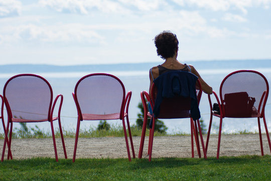 Older Woman Sitting In A Chair Facing The Horizon In Retirement